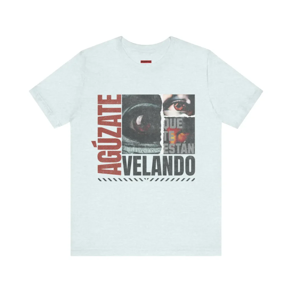 Tshirt heather ice blue de unos ojos mirando fijamente y el texto agúzate que te están velando en color blanco, negro y anaranjado.